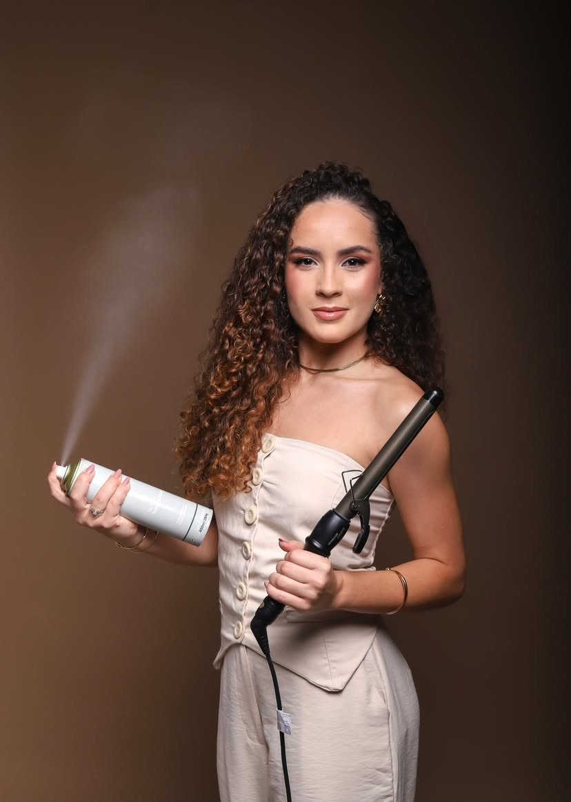Larissa Lima segurando um babyliss e um spray finalizador